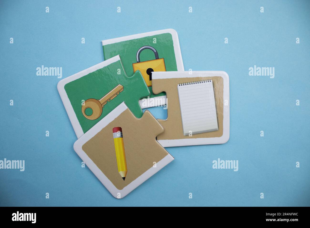 Picture puzzles superimposed on a blue background. Pen, notebook, key and lock. Mixed. Stock Photo