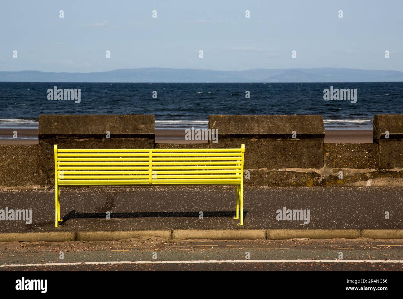 Yellow public bench seat at a coastal seafront location Stock Photo