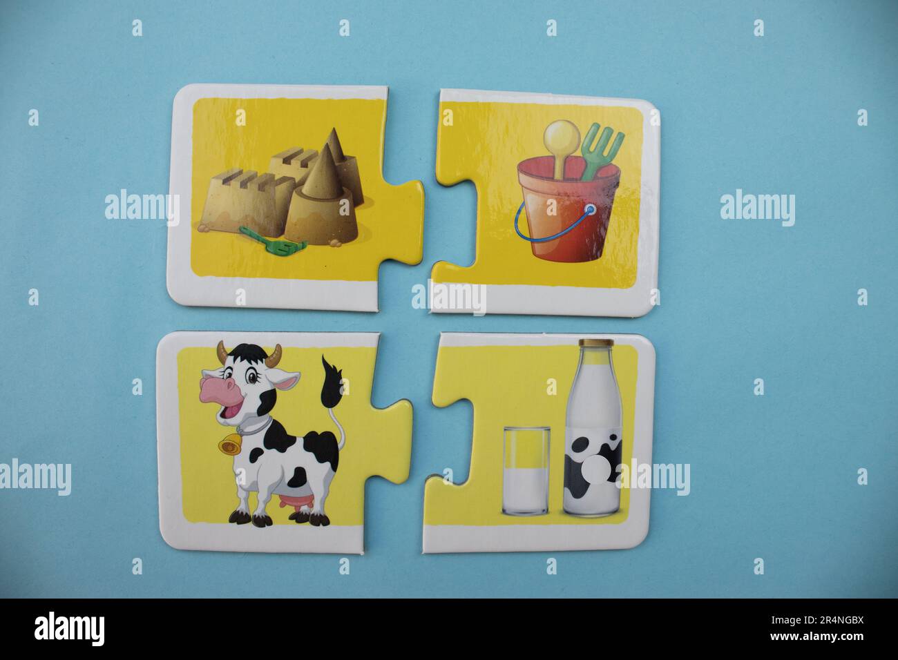 Information puzzles placed on a blue background. Cow, milk, sand and bucket. Stock Photo