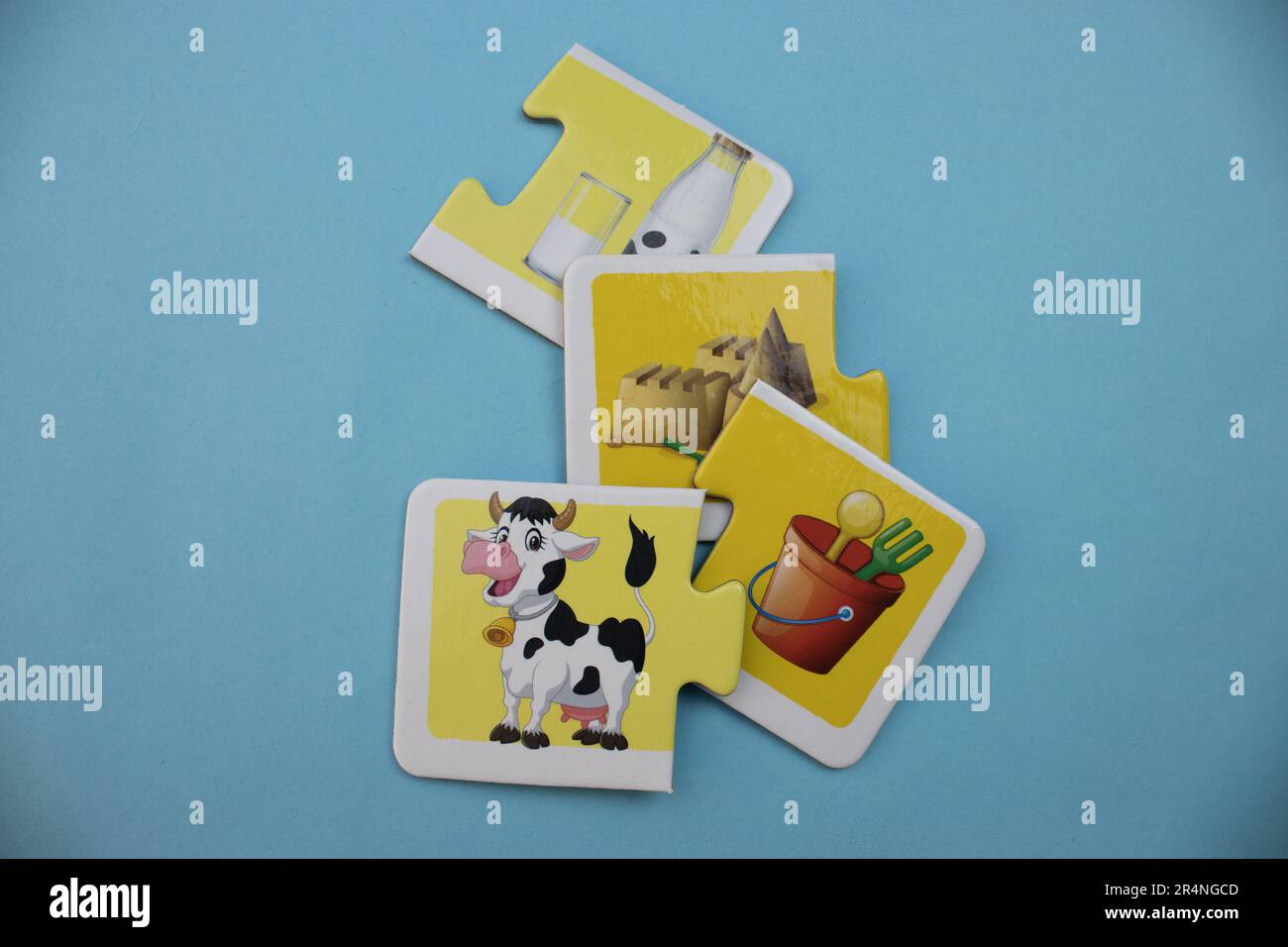 Picture puzzles placed on a blue background. Cow, milk, sand and bucket. Mixed. Stock Photo