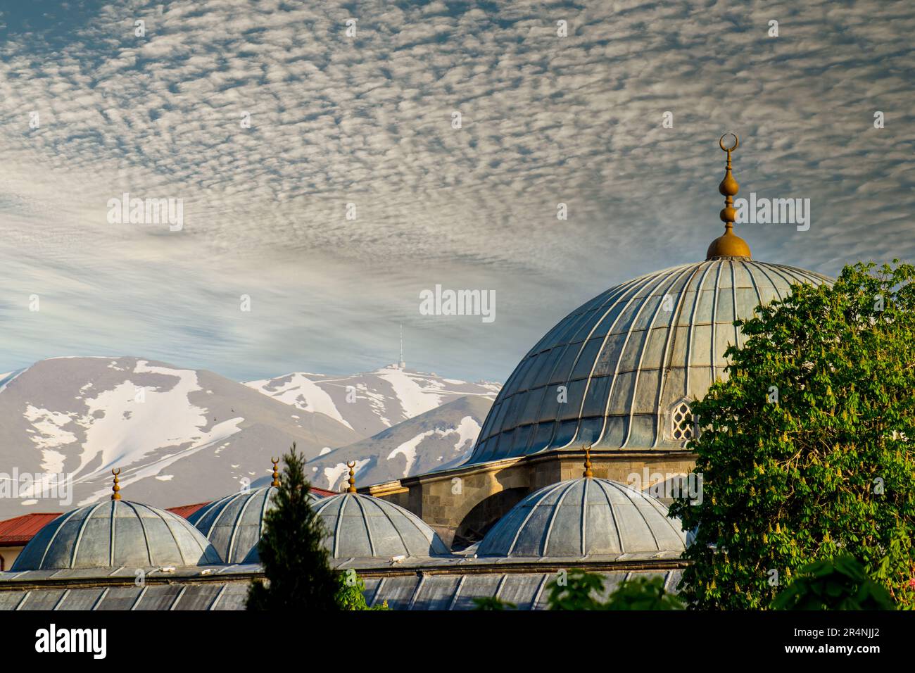 A view of a mosque with the mountains in the background. Turkish : Erzurum Lalapasa Camii Stock Photo