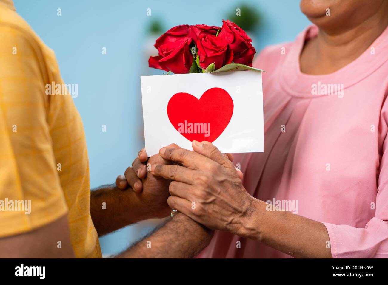 Close up shot of adult son giving greeting card with flowers to senior mother at home - concept of mother's day wishing, family bonding and motherhood Stock Photo