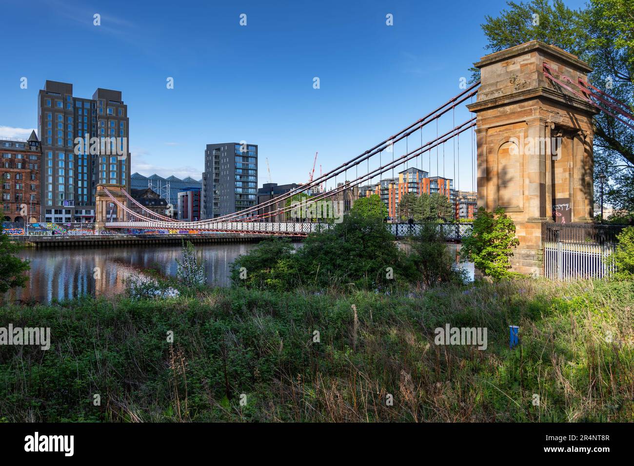 City skyline of Glasgow with South Portland Street Suspension Bridge in Glasgow, Scotland, United Kingdom. Footbridge from 1853 across the River Clyde Stock Photo
