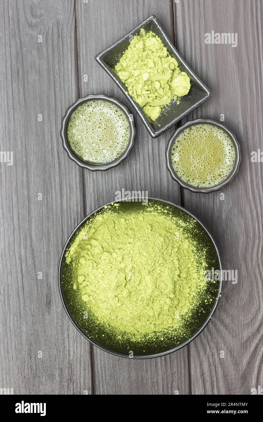 Green matcha tea powder in a black bowl. Matcha tea in a bowl. Flat lay. Dark wooden background. Stock Photo