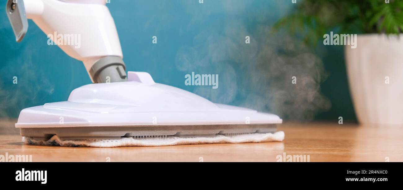 A man washes the floors with a steam mop. Floor treatment with hot steam. Hygienic control of ...