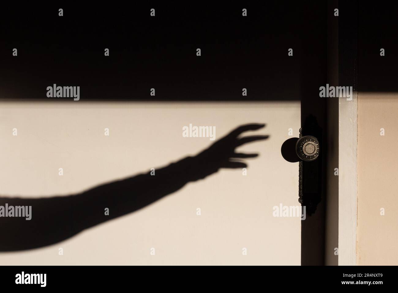 Goiania, Goias, Brazil – May 17, 2023: The shadow of an arm with a hand trying to open a closed white door. Stock Photo