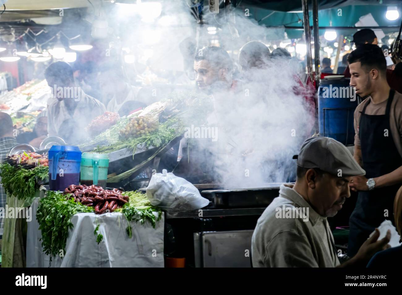 Chefs preparing Moroccan street food in an outdoor night time market food stall in Jemaa el Fna square, Marrakesh. Stock Photo