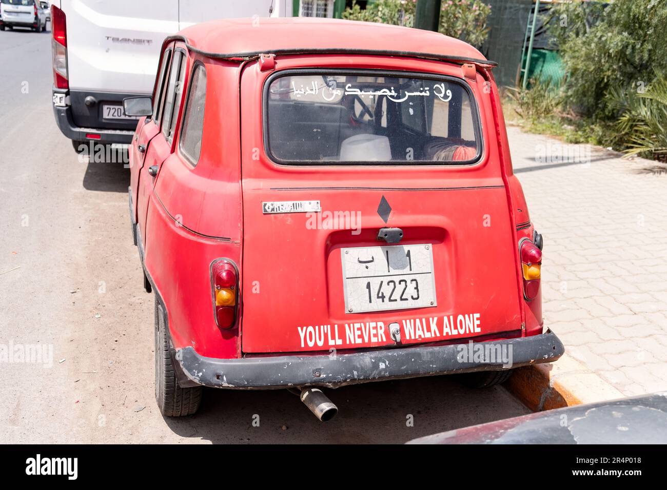 An old red Renault 4 motor vehicle parked on a street in Marrakesh, Morocco. The car has the slogan You'll Never Walk Alone written across its boot Stock Photo