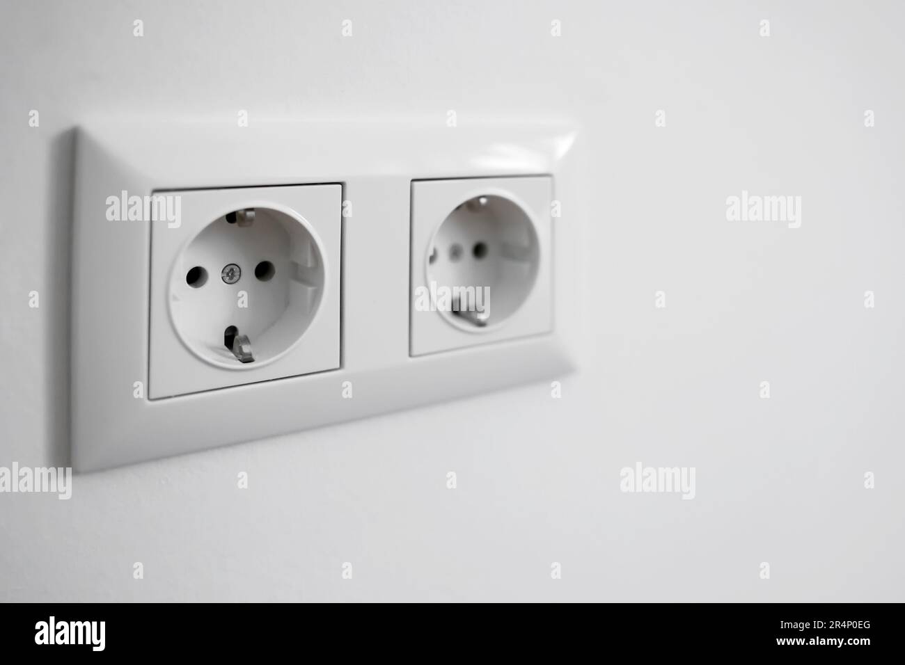 Electric sockets on white wall, closeup Stock Photo - Alamy