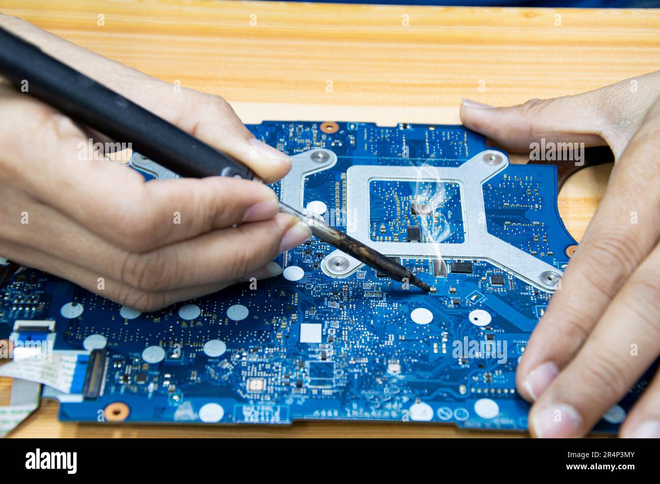 Motherboard repair. Motherboard, solder parts, male, close-up. Stock Photo