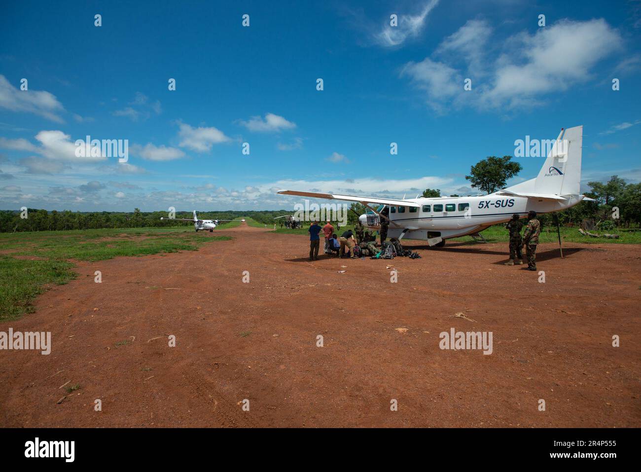 A Cessna 208 Caravan Aircraft Being Loaded on A Dirt Landing Strip Near a-cessna-208-caravan-aircraft-being-loaded-on-a-dirt-landing-strip-near