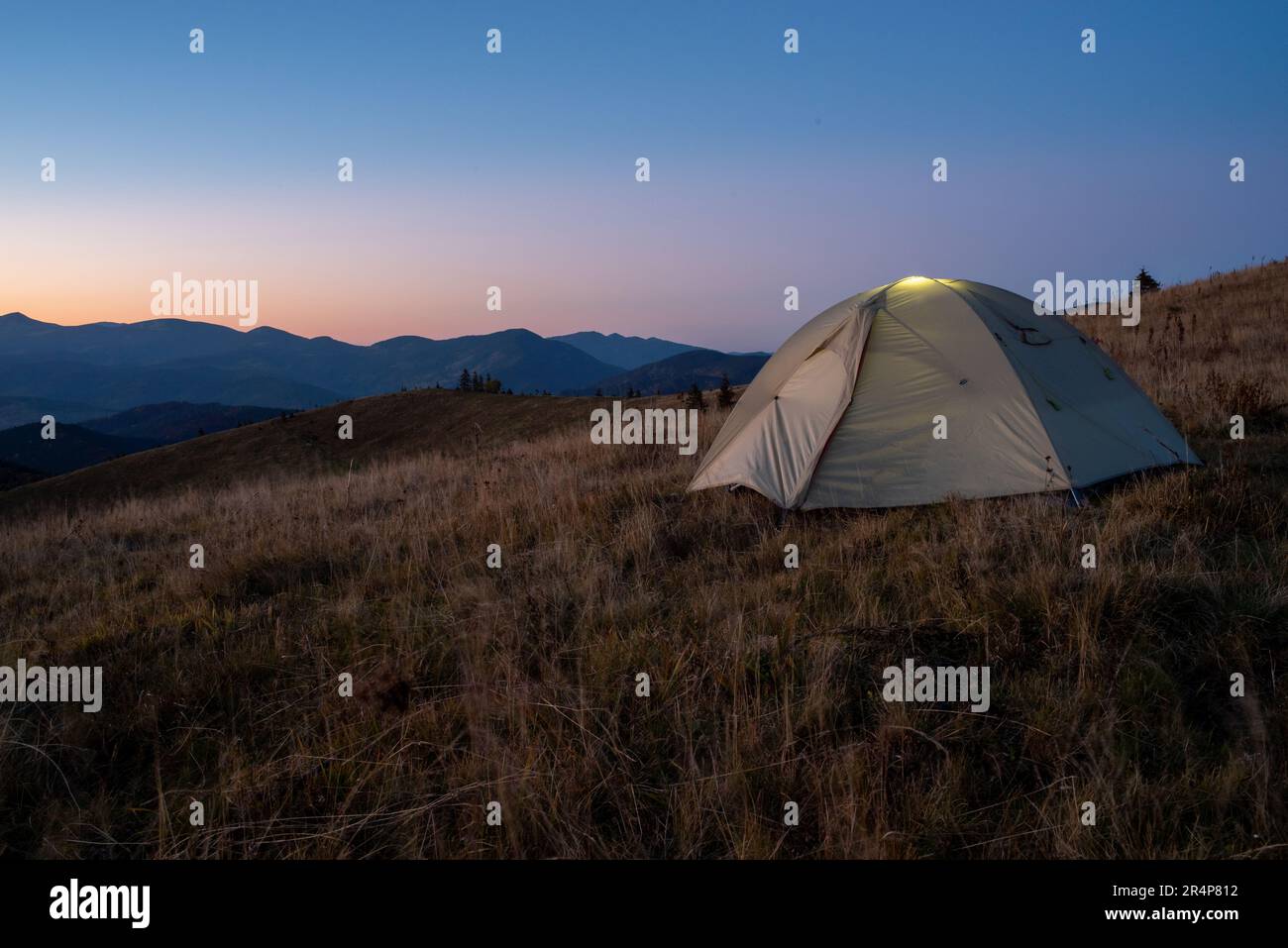 A tourist tent stands on top of a mountain. Camping at the top of the ...