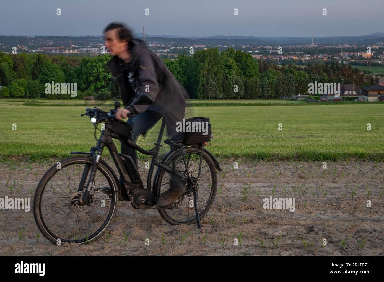 Electric bike with black bag on meadow and field near Budweis in sunny evening Stock Photo