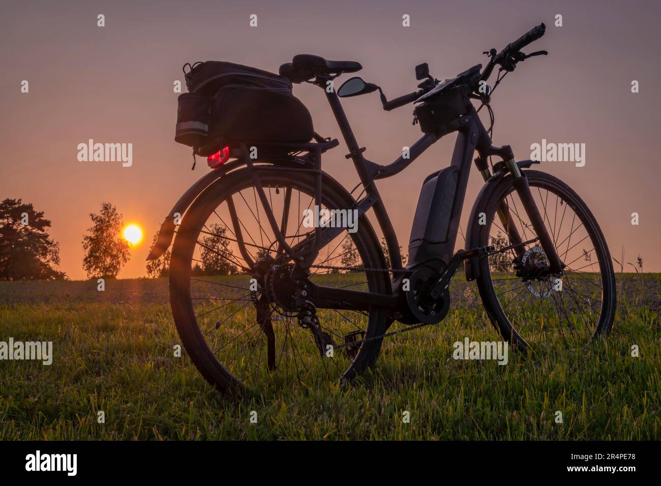 Electric bike with black bag on meadow near Budweis with after sunset orange sky Stock Photo