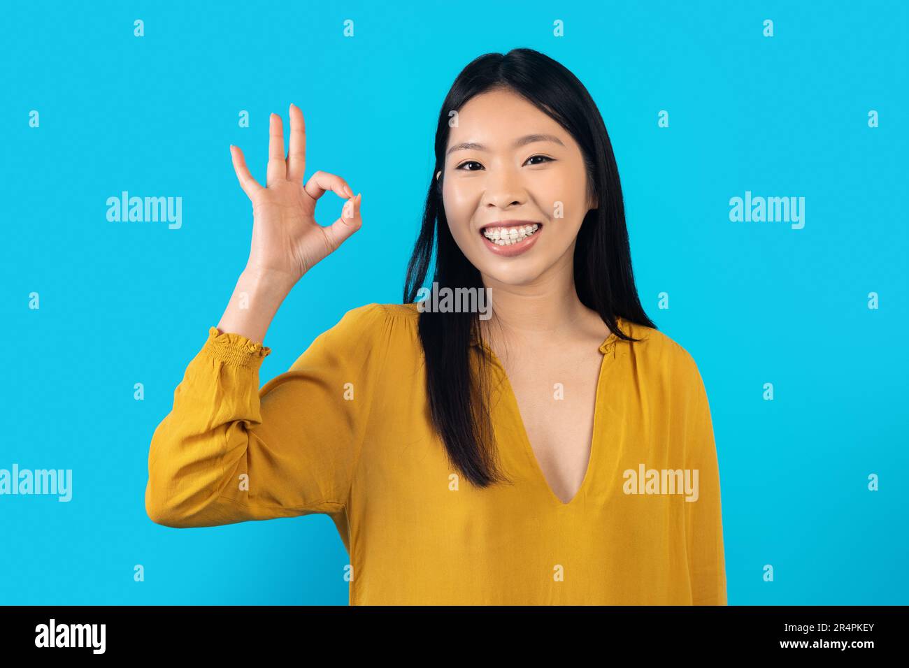 Positive young asian woman showing okay gesture and smiling Stock Photo ...
