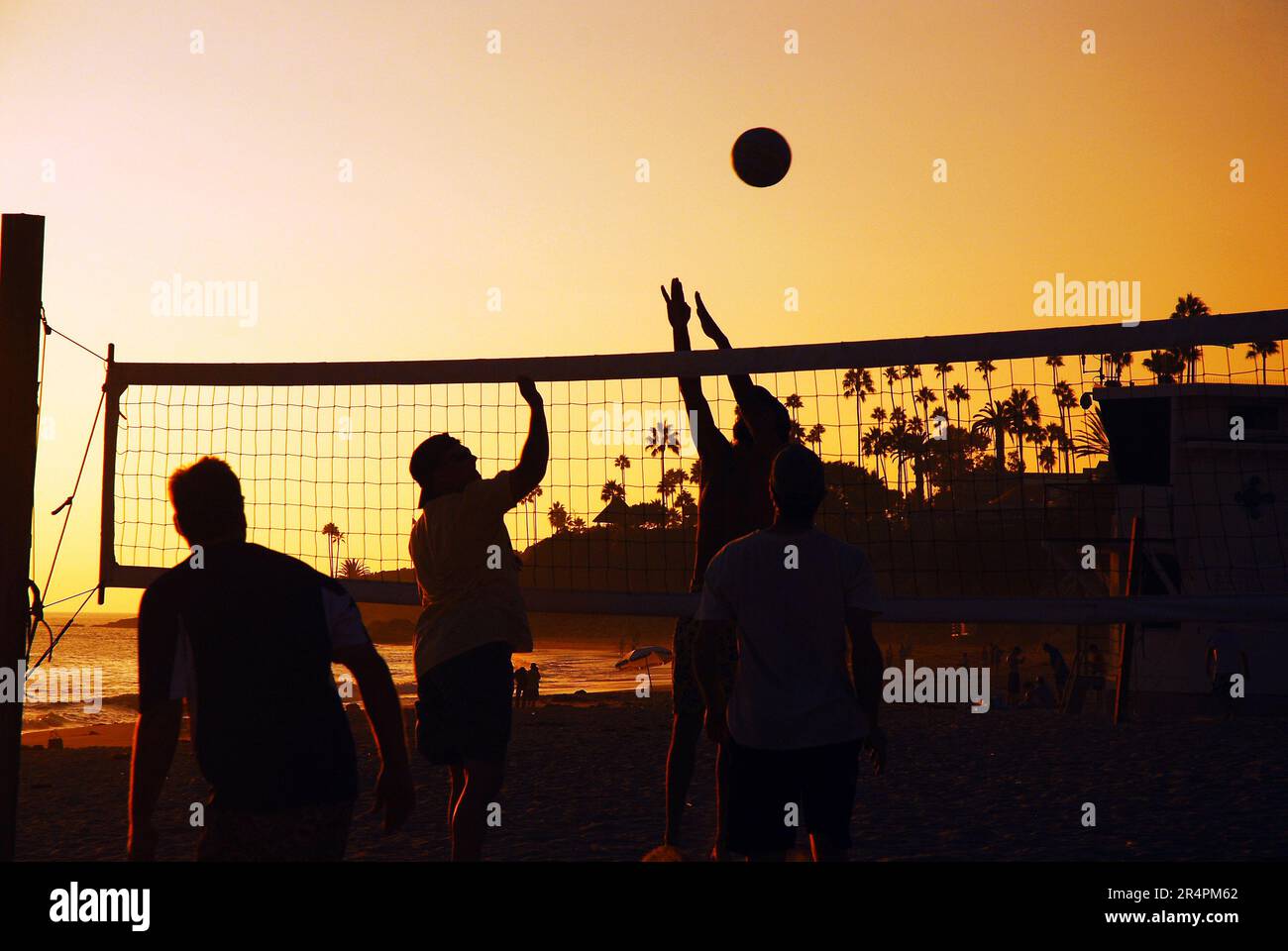 Young adults play a friendly game of beach volleyball in Laguna Beach at sunset Stock Photo