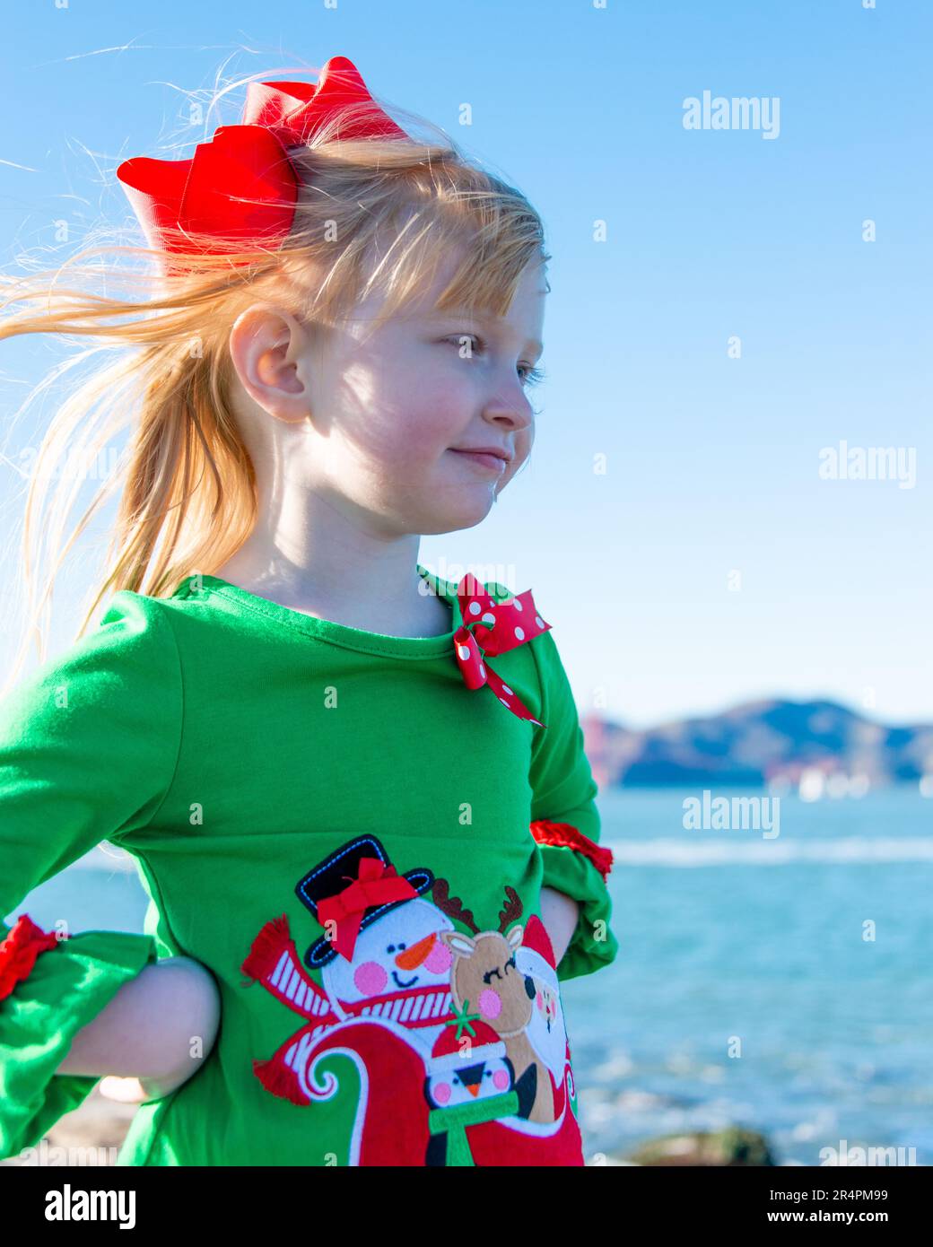 Threeyearold girl wearing a Christmas shirt and red bow in her hair