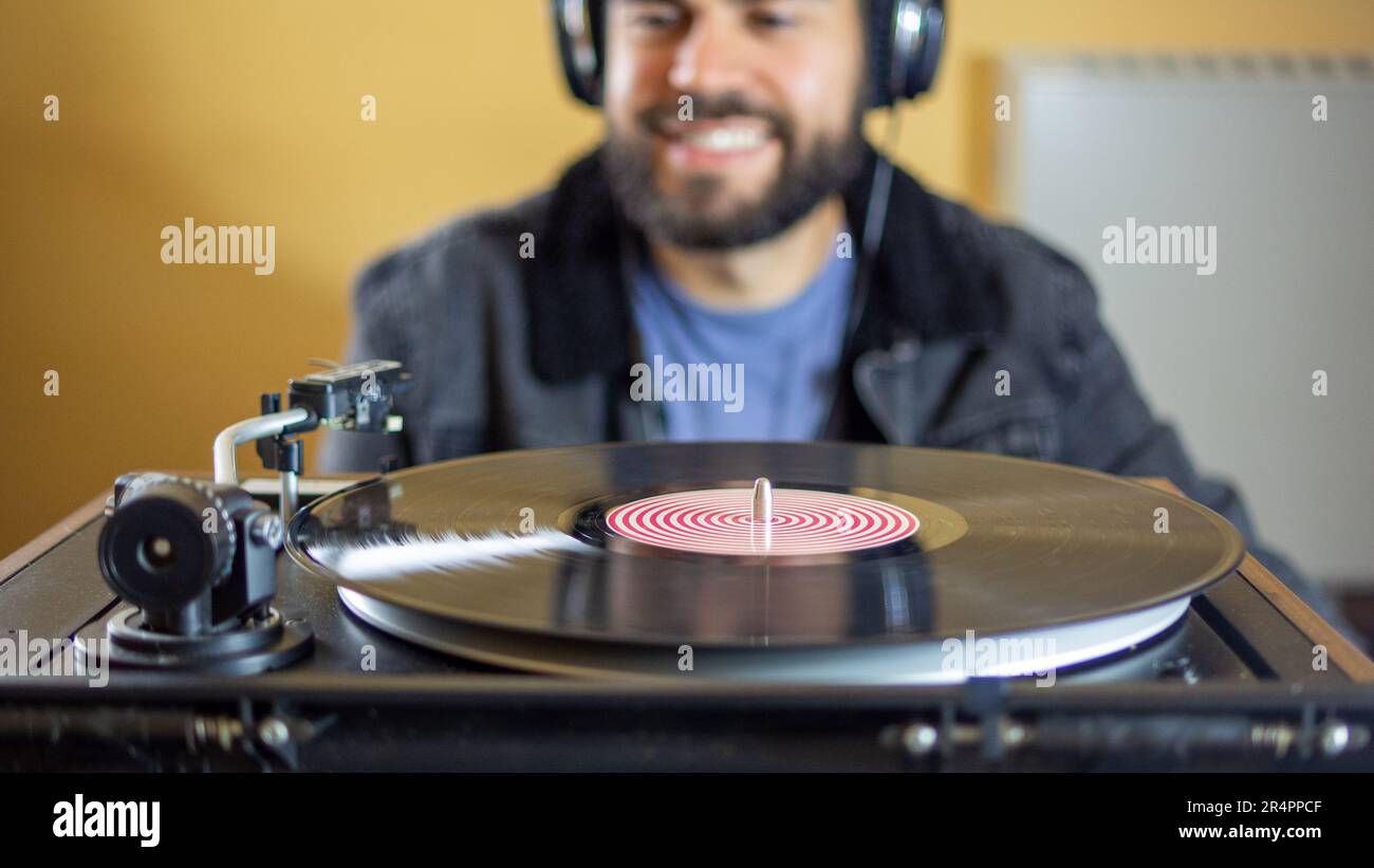 Young man using headphones while playing a vinyl record on a vintage
