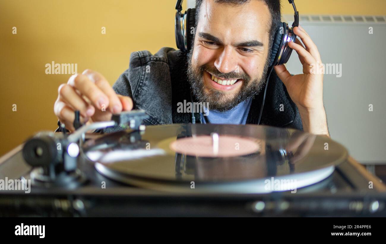 Young man using headphones while playing a vinyl record on a vintage turntable Stock Photo
