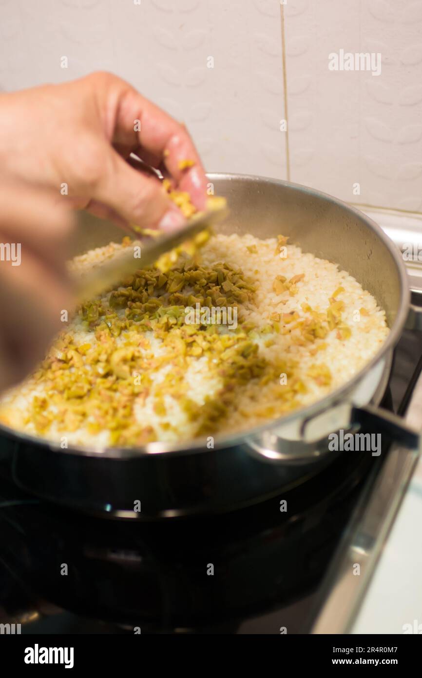 Photo inspiration: Basic Steps To Cook Rice With Chopped Preserved Peppers And Reference: Human Hand Adding Chopped Green Olives To Rice Kitchen Stock