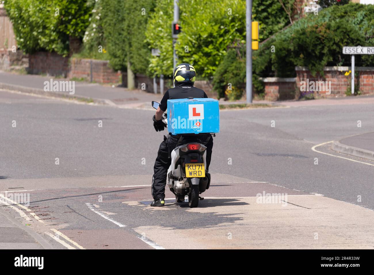 A moped rider with an L Plate delivering pizza for Dominos Pizza, Basingstoke, UK. Concept: fast food delivery, gig economy, trainee employee Stock Photo