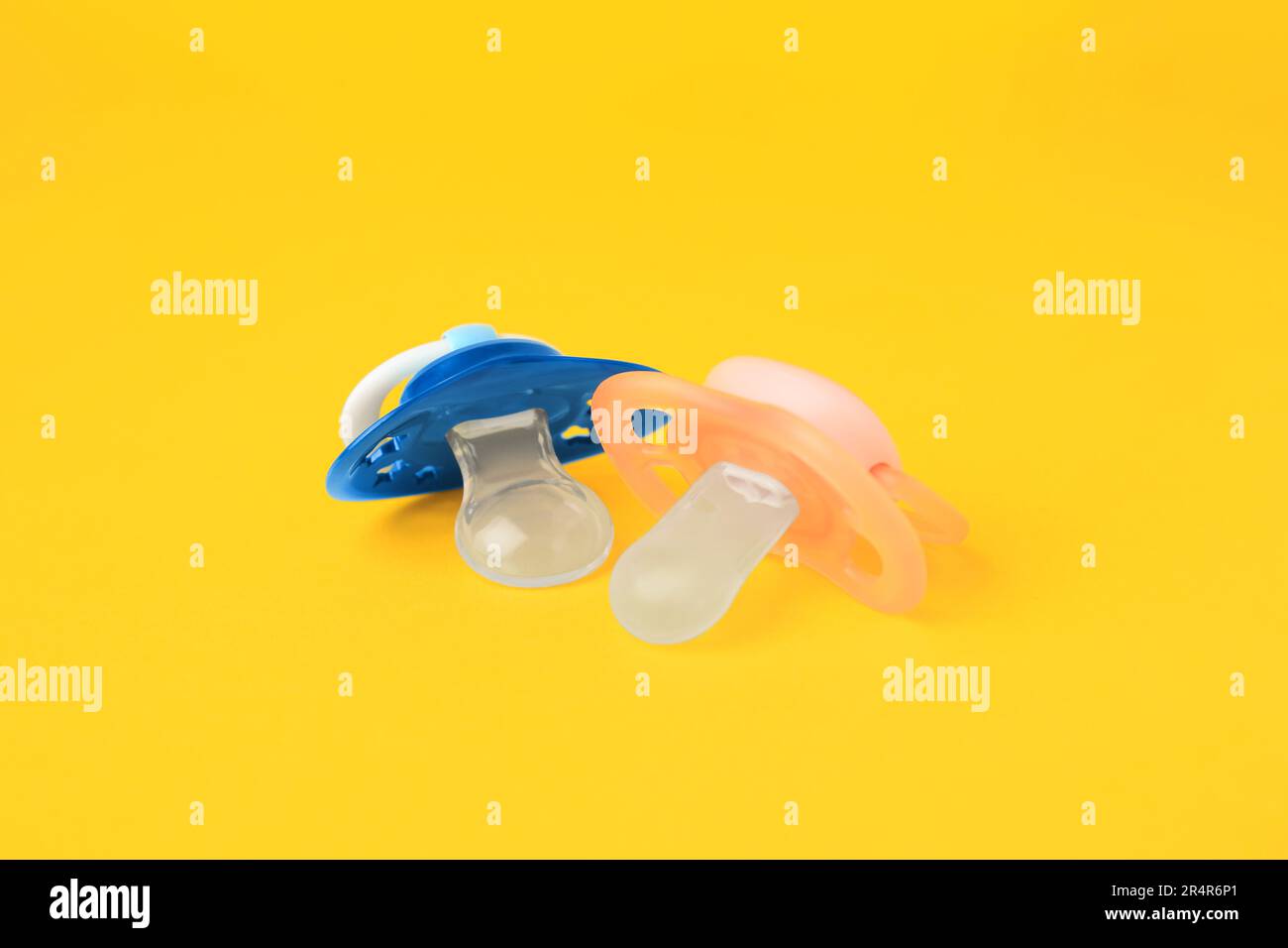 Colorful baby pacifiers on bright orange background Stock Photo