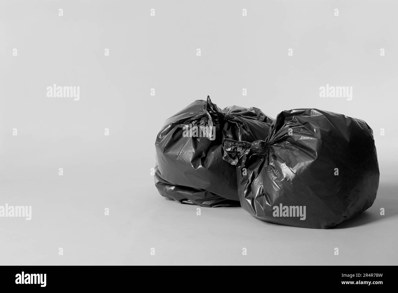 Trash bags full of garbage on light grey background. Space for text ...