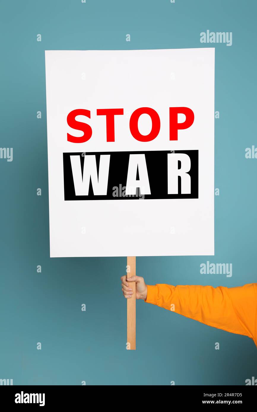 Woman holding poster with words Stop War on light blue background, closeup Stock Photo