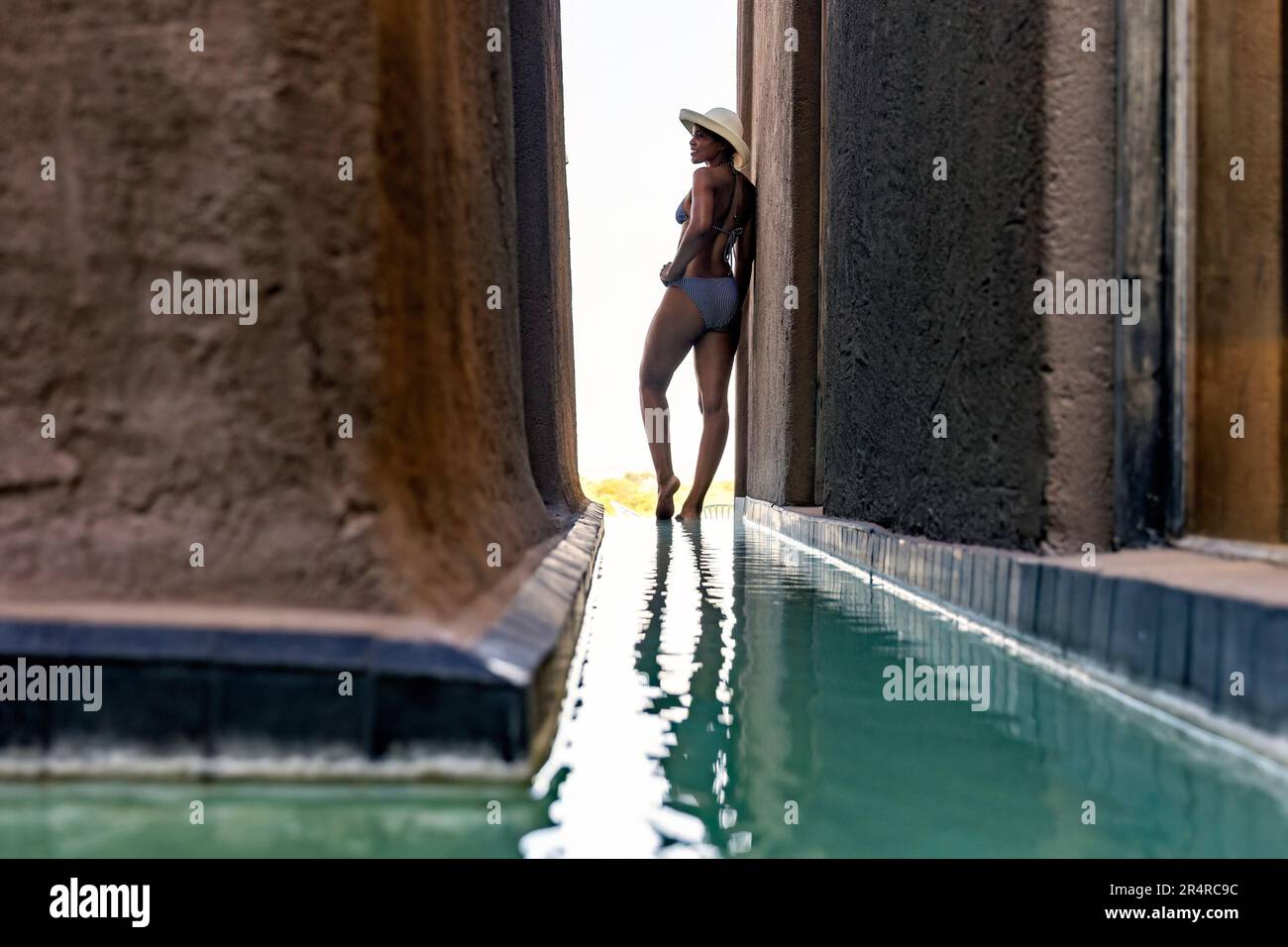 Attractive model standing by reflection pool at Onguma The Fort, Onguma Game Reserve, Namibia, Africa Stock Photo