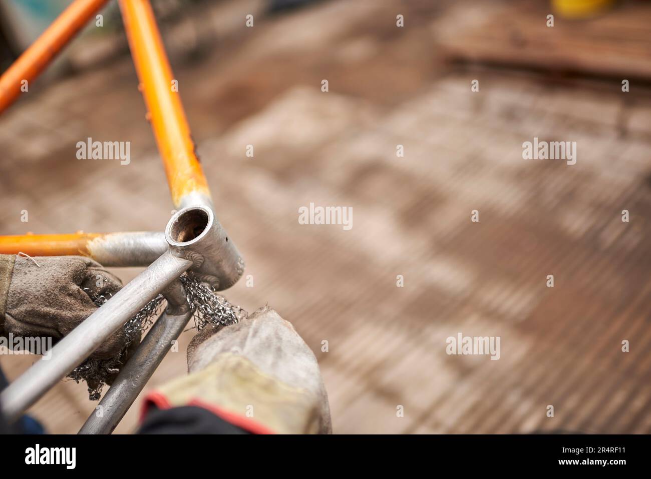 Manual work unrecognizable worker using steel wool over a bicycle frame after passing a