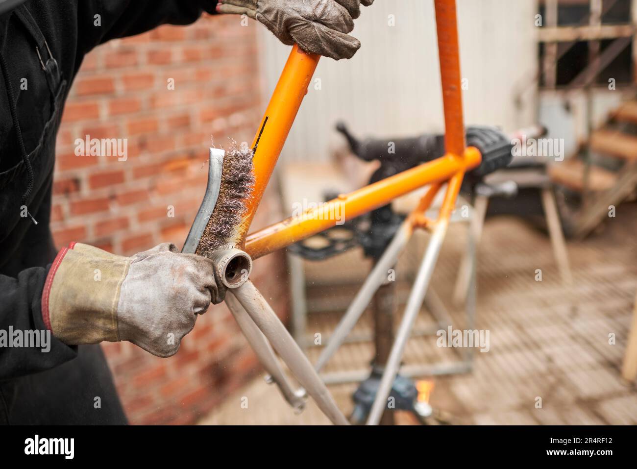 Unrecognizable man using a wire brush over a bicycle frame after