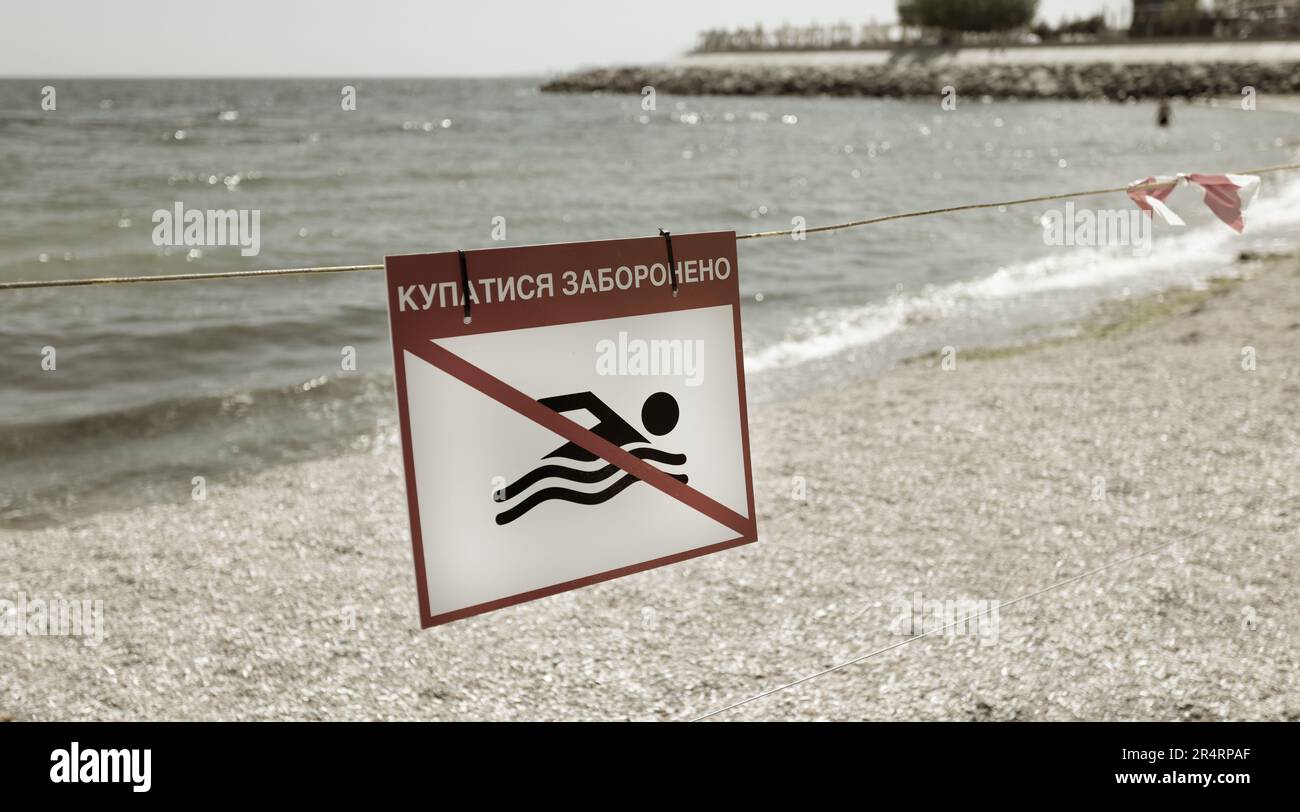 bright red 'No Swimming' sign on city's sea sandy beach in Odessa during Russia's attack on Ukraine. Swimming is prohibited! Approaching the water is Stock Photo