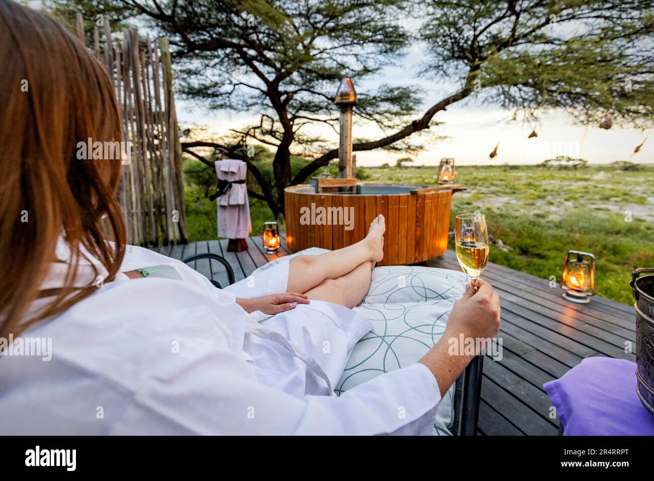 Woman enjoying a drink on the deck of the Honeymoon Suite - Onguma The Fort, Onguma Game Reserve, Namibia, Africa Stock Photo
