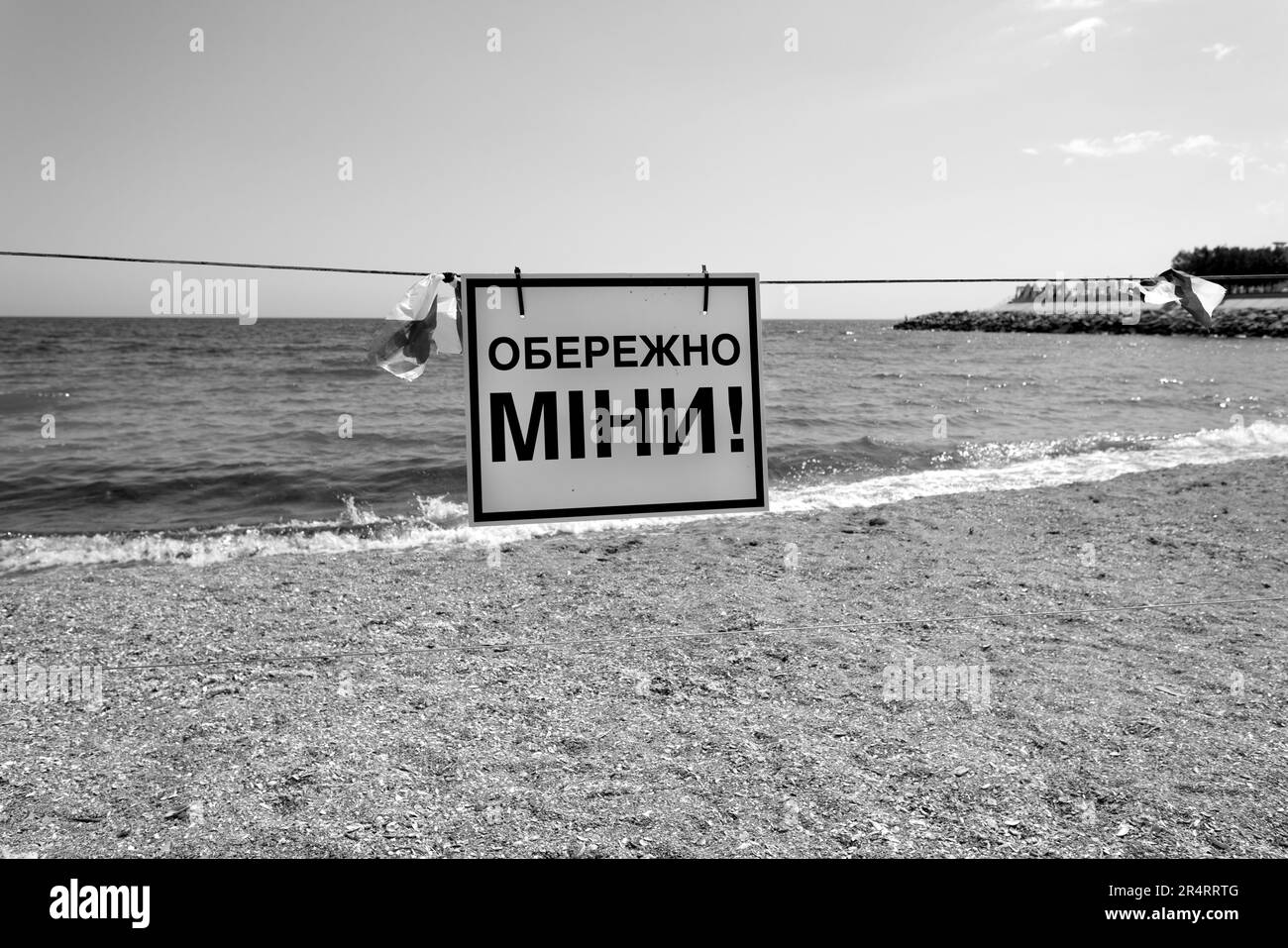 A bright red 'Danger-mines' sign in Ukrainian is placed on the city's sea sandy beach in Odessa during Russia's attack on Ukraine. Swimming is prohibi Stock Photo