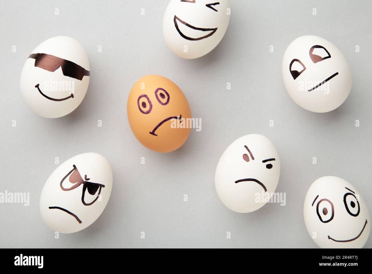Eggs with different emotions on his face. Easter composition with copy space on grey background. Stop racism. Top view Stock Photo
