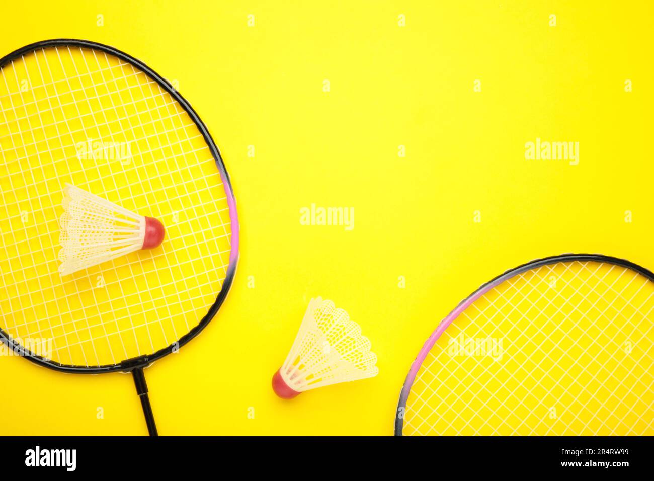 Shuttlecocks and badminton rackets on yellow background. Top view. Stock Photo