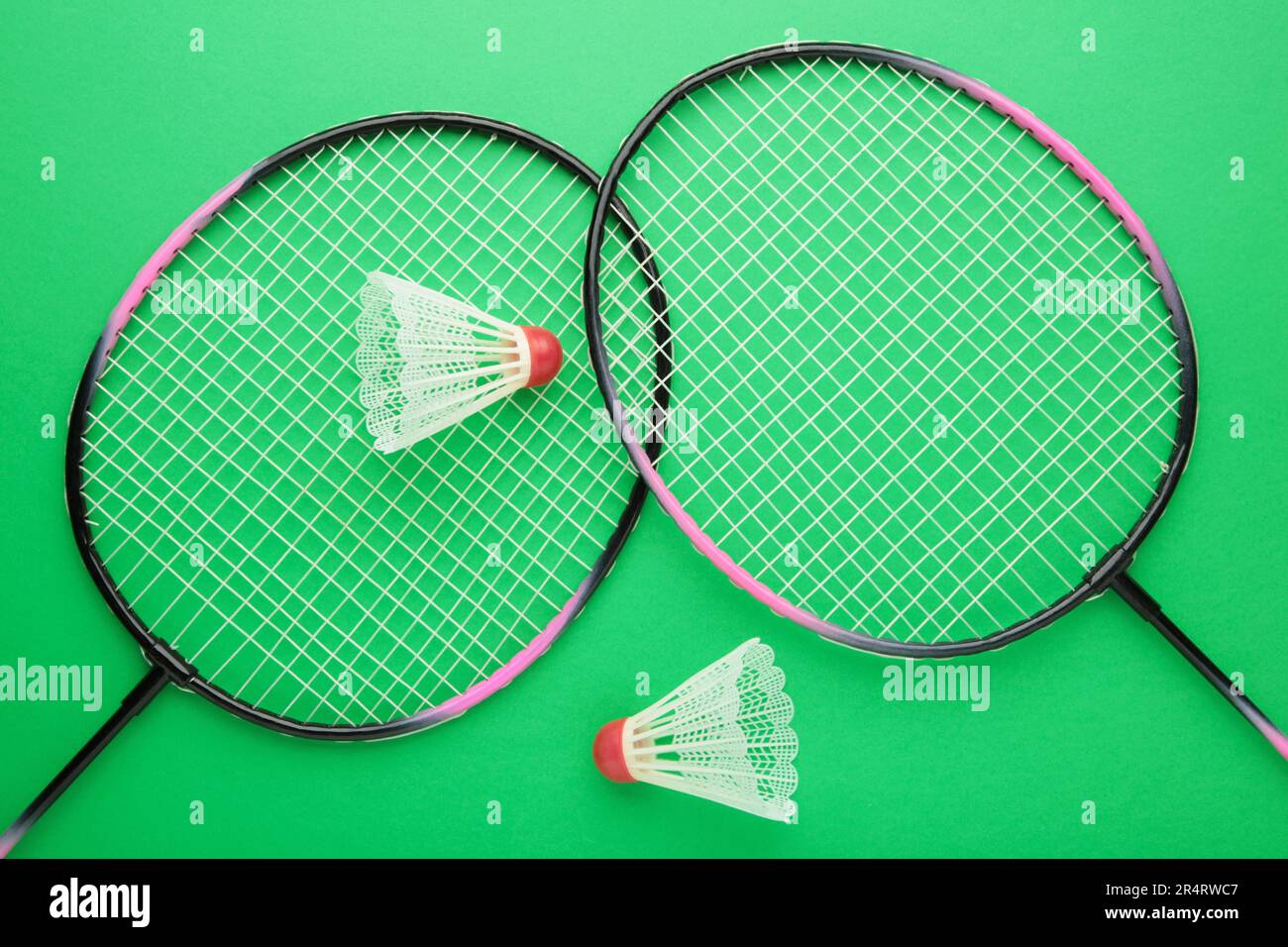 Shuttlecocks and badminton rackets on green background. Top view. Stock Photo