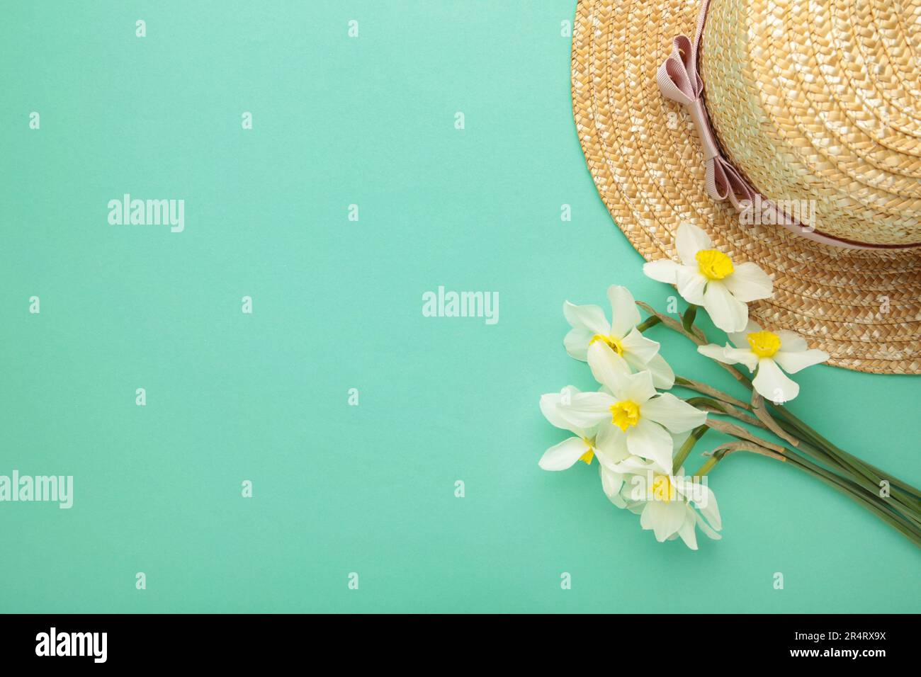 Straw hat with spring flowers on mint background. Top view Stock Photo