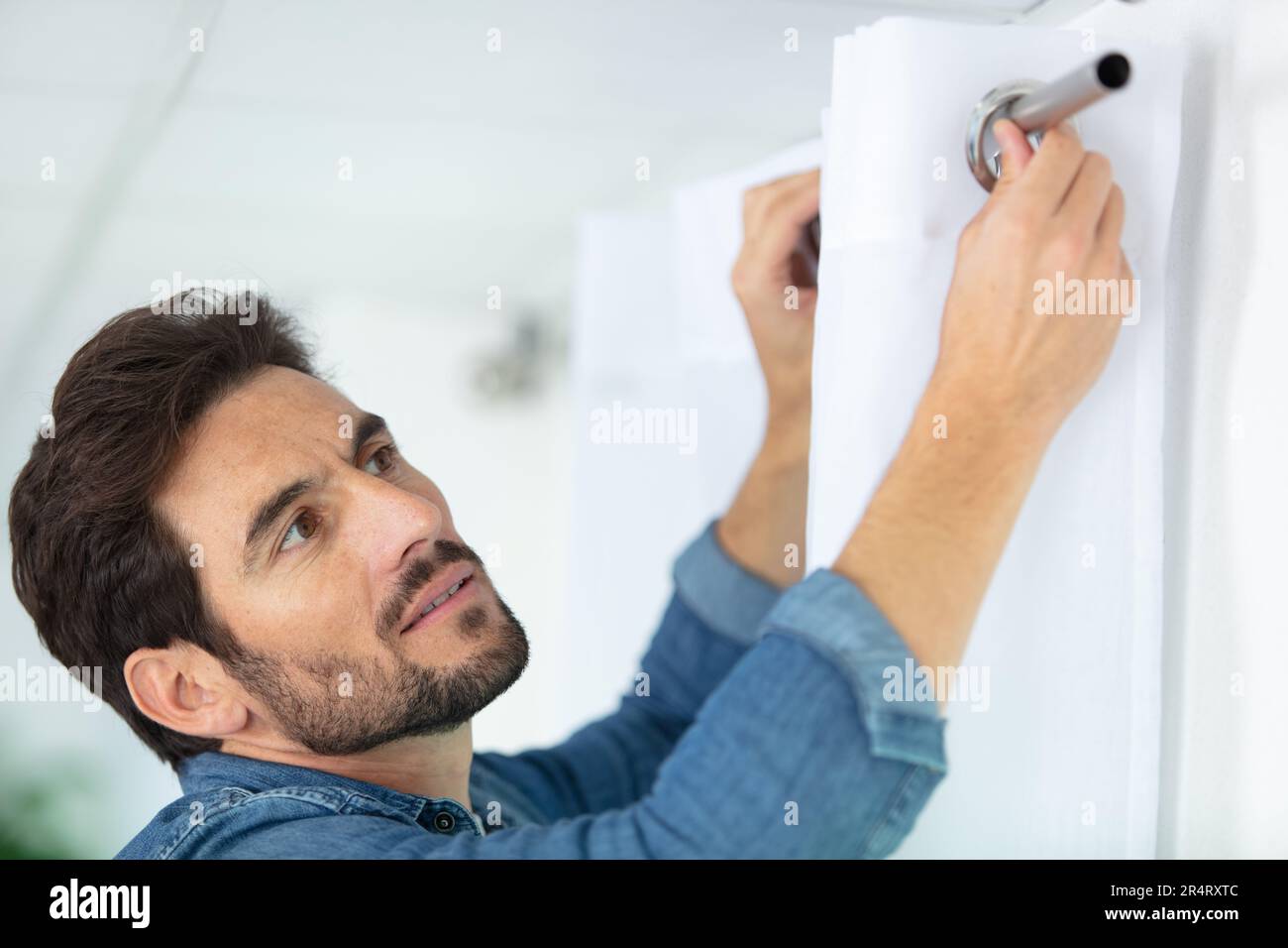 young man installing curtains over window Stock Photo