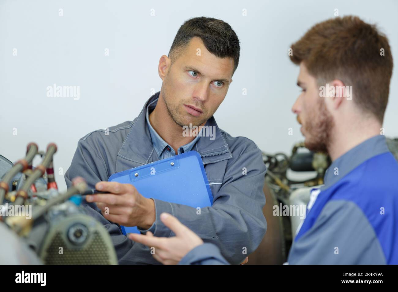 engineer teaching apprentices to use computerized metal processing machines Stock Photo
