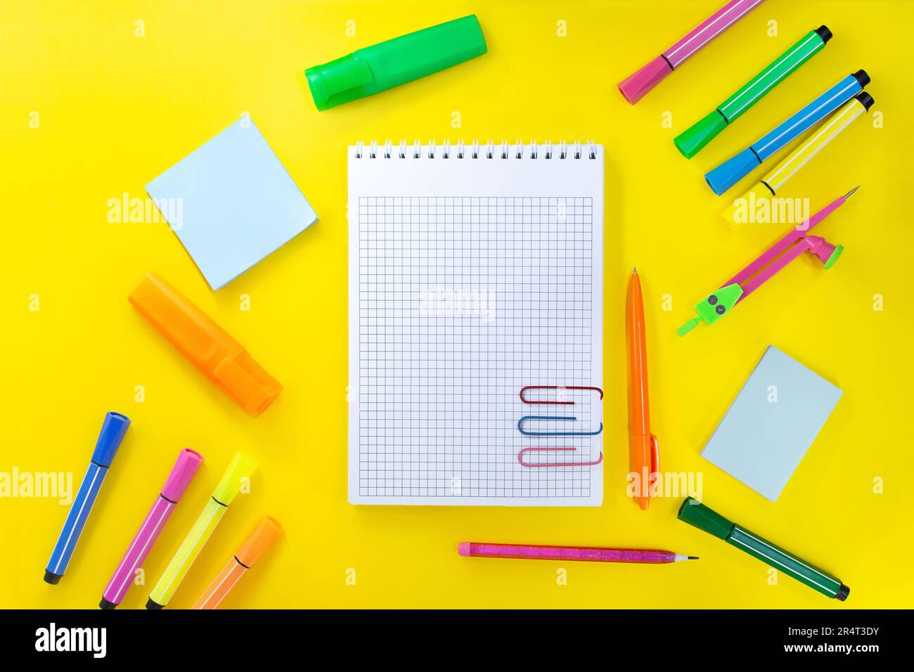 Back to school, drawing. Notebook checkered with pencil for notes to text with paper clips. Near pink, orange, green stationery. Markers, felt-tip pen Stock Photo
