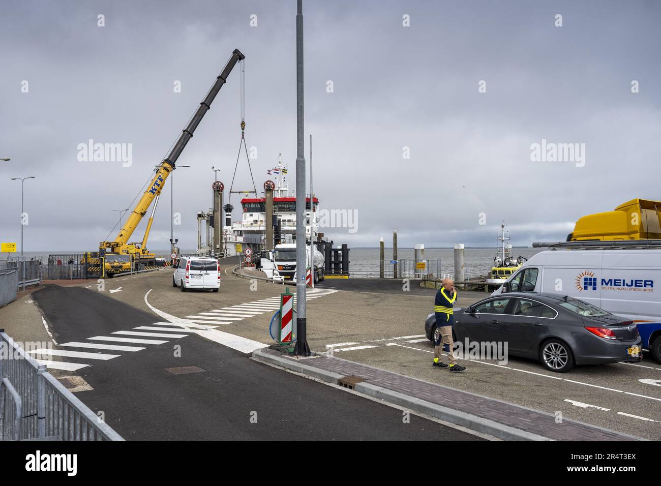 HOLWERT - A crane operates the car bridge so that cars can drive on and off the boat again. The ferry service between the mainland and Ameland has resumed after problems with the car bridge in the harbor of Holwert prevented travelers from disembarking with a car, so they were taken back to Ameland. ANP JILMER POSTMA netherlands out - belgium out Stock Photo
