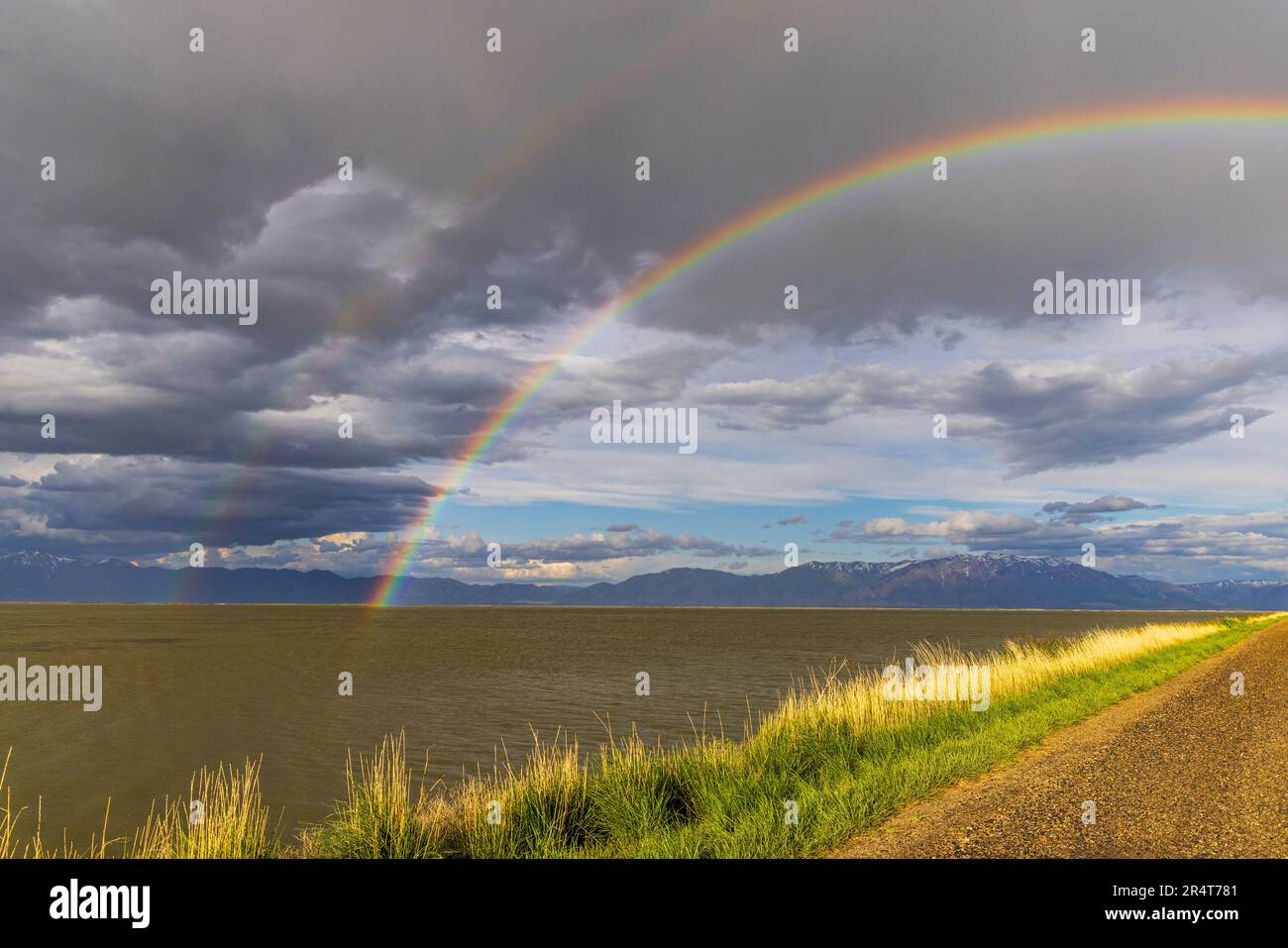 A spectacular double rainbow arcs over the water of Unit 2 and the Auto Tour Road at Bear River Migratory Bird Refuge near Brigham City, Utah, USA.. Stock Photo
