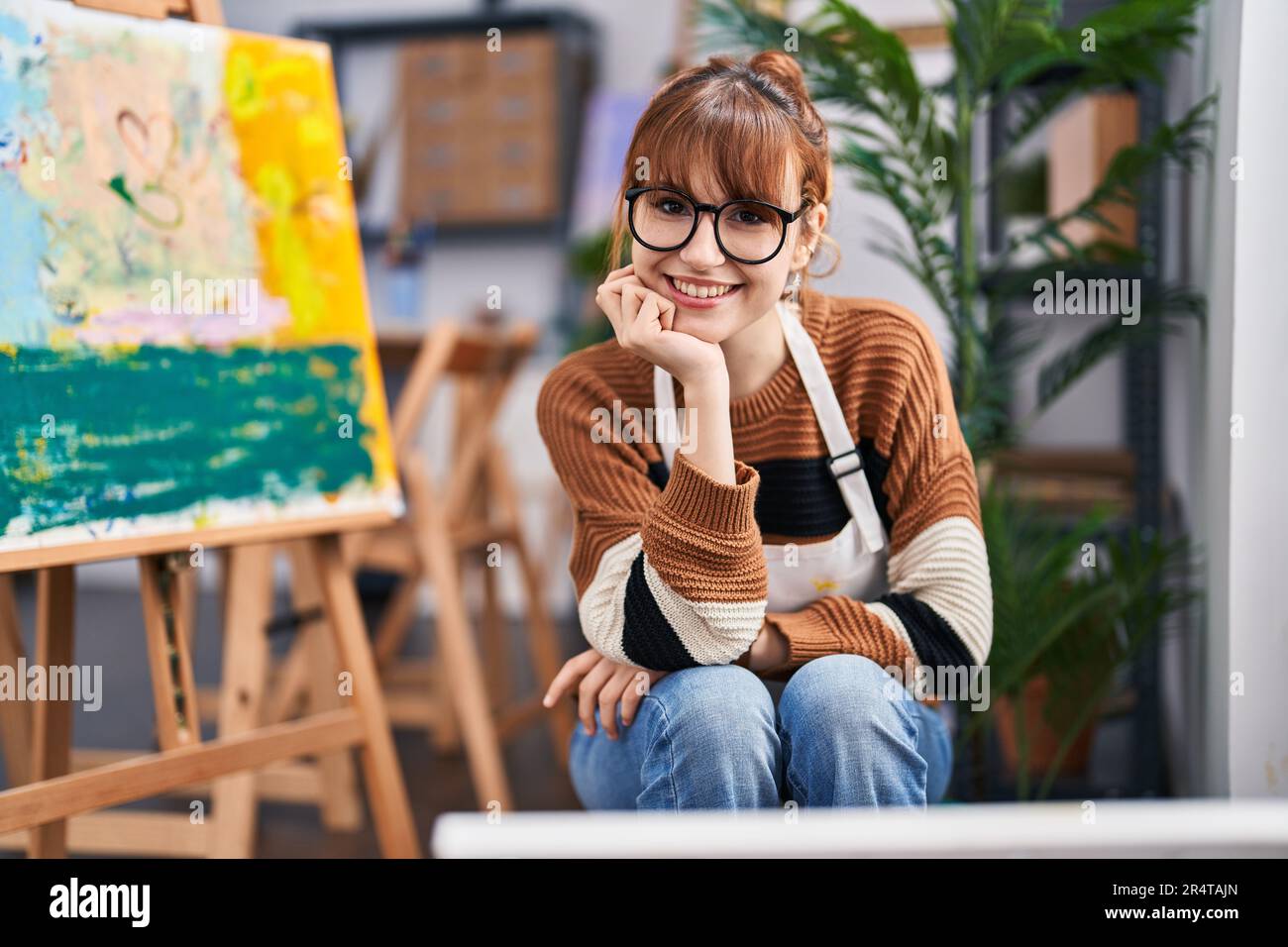 Young woman artist smiling confident sitting on chair at art studio ...