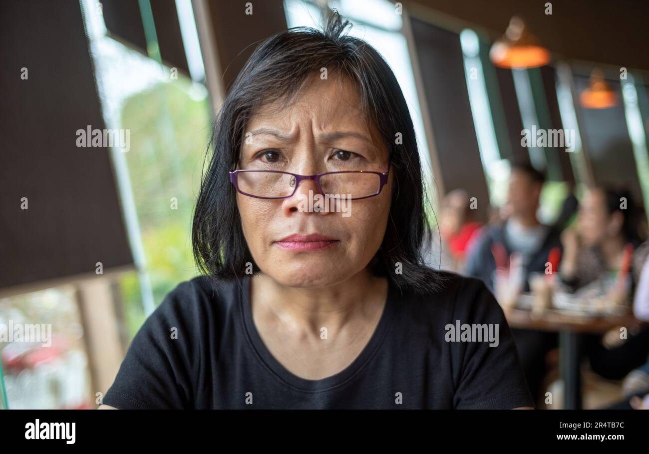 A Vietnamese woman looks puzzled as she gazes at the camera in a coffee shop in Danang, Vietnam Stock Photo