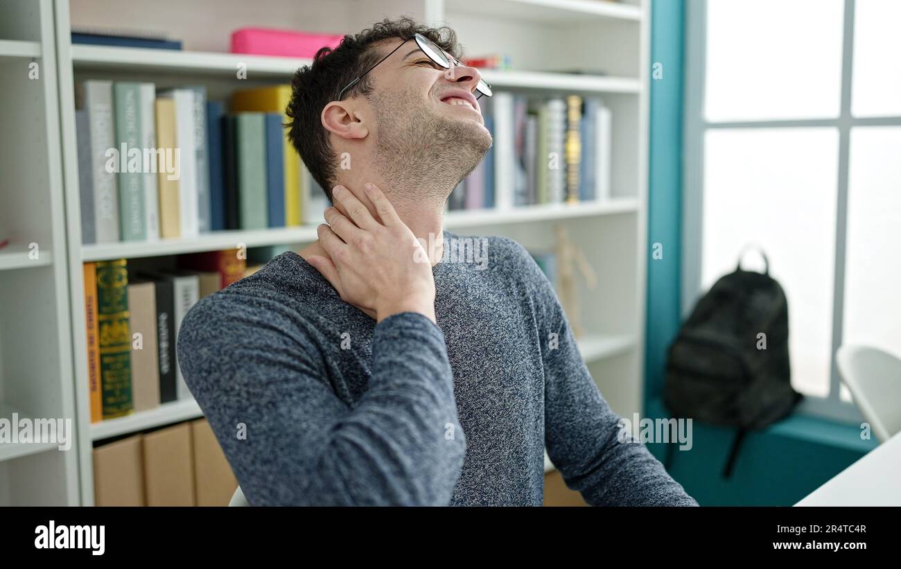 Young hispanic man student using computer stressed at library ...