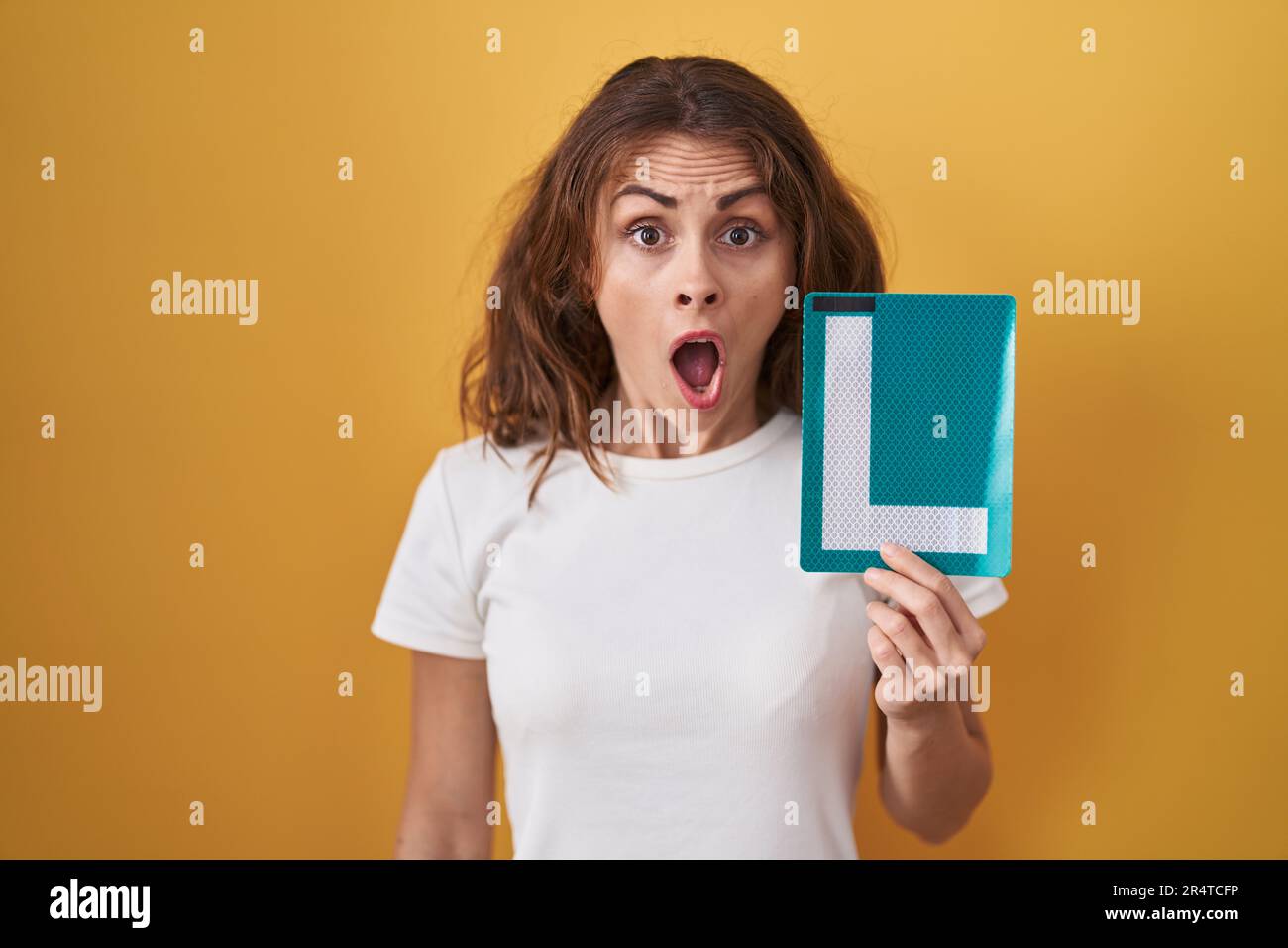 Beautiful brunette woman holding l sign for new driver scared and ...