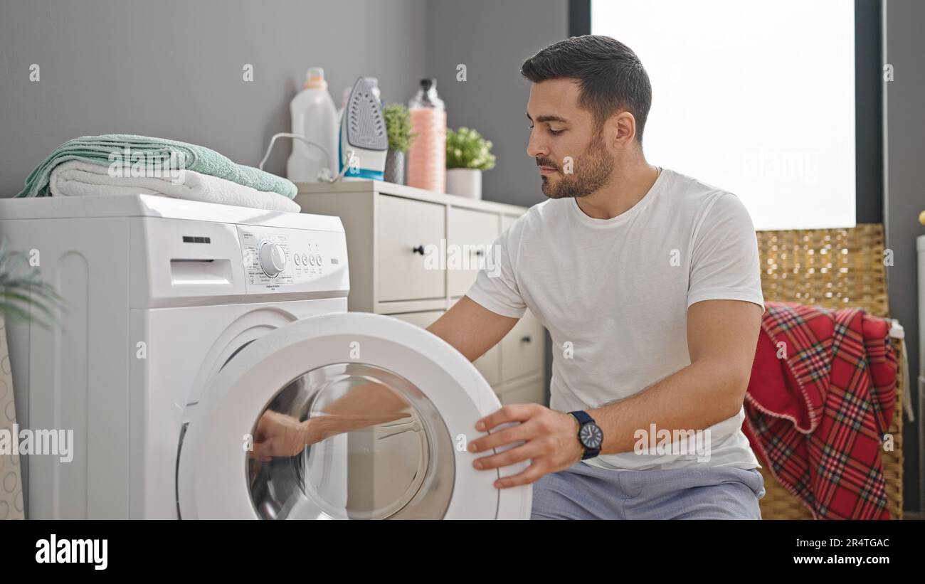 Young hispanic man doing laundry at laundry room Stock Photo