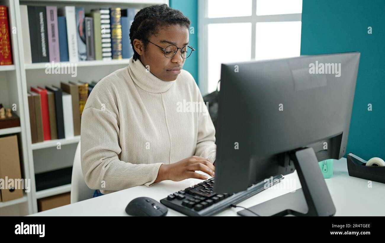 African american woman student using computer studying at library ...