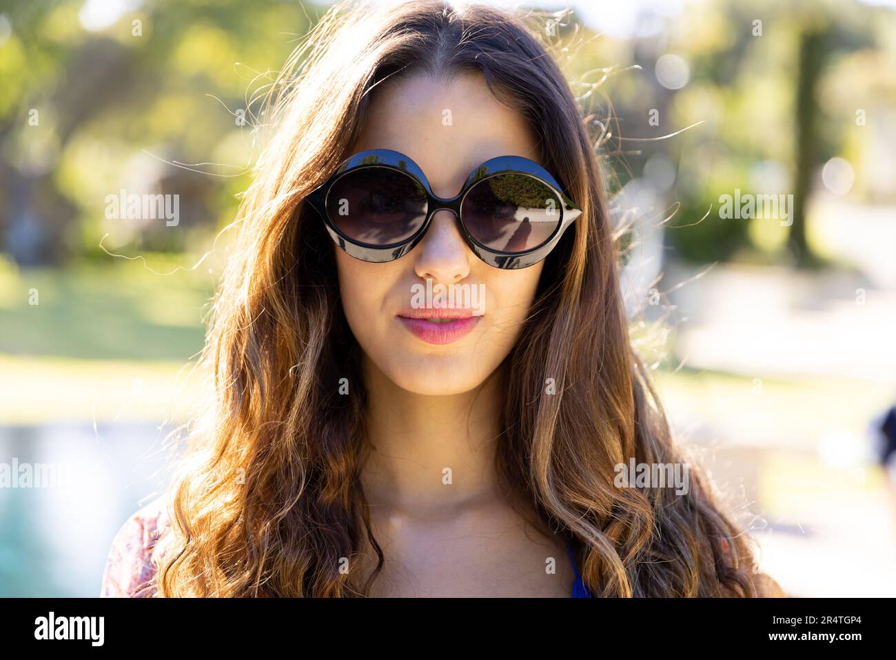 Close-up portrait of biracial attractive young woman wearing sunglasses and posing in yard Stock Photo